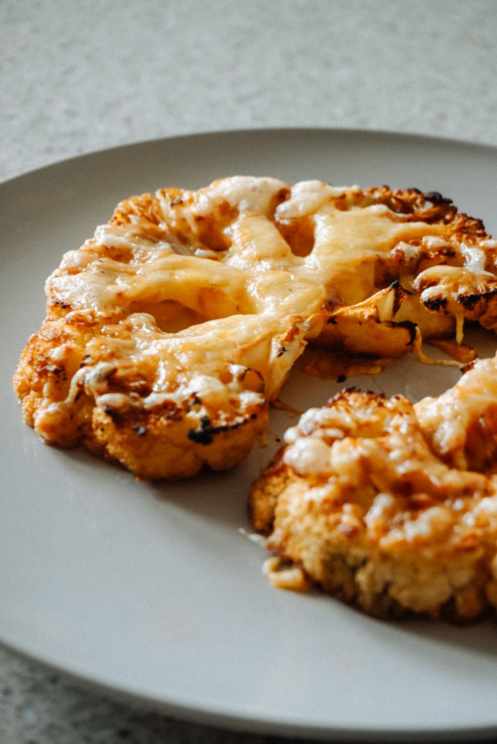 Delicious cheesy roasted cauliflower steaks on a plate, perfect for a healthy meal.
