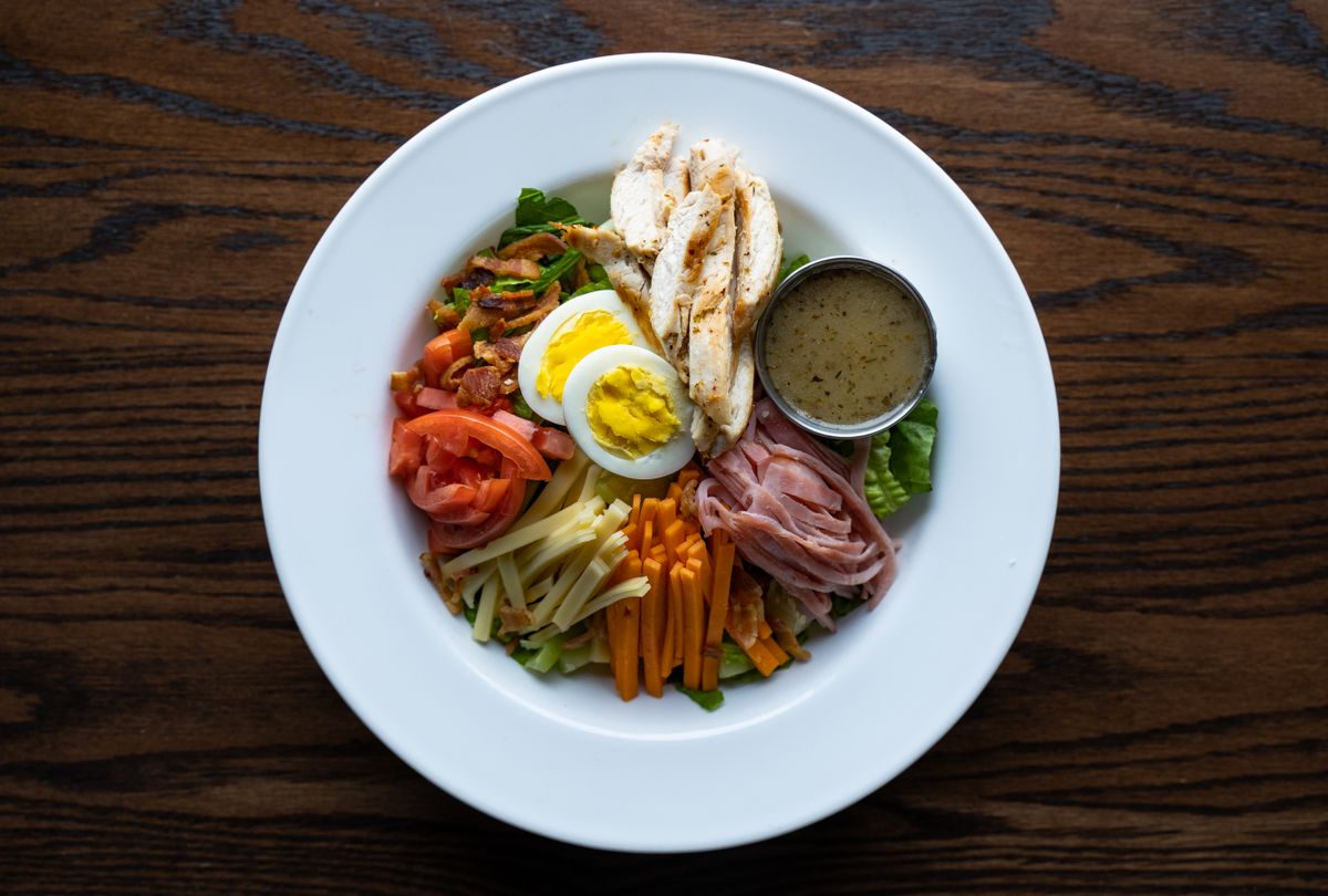 Delicious Cobb salad with chicken, eggs, and vegetables on a ceramic plate.