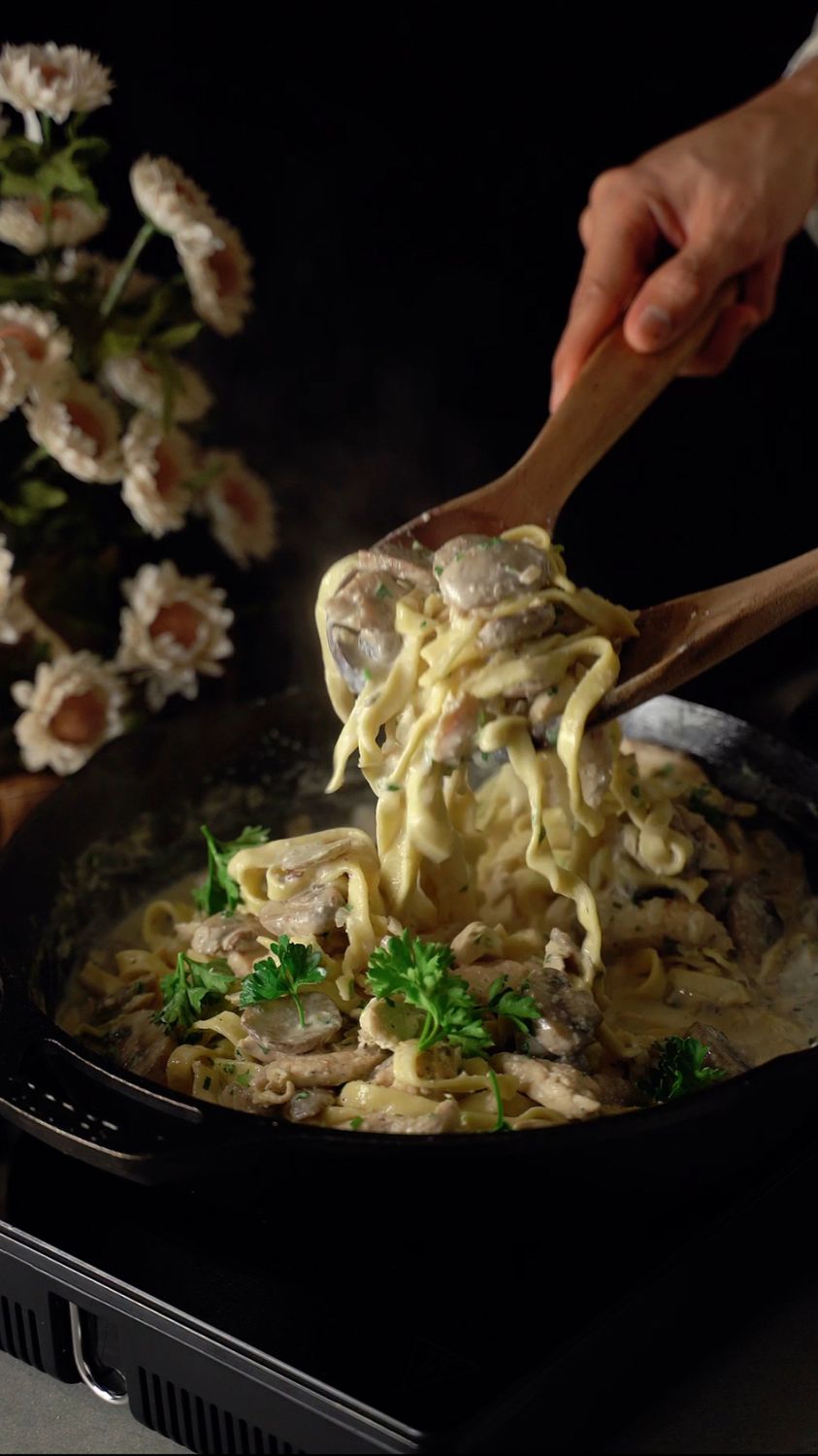 7 One-Pot Comfort Dinners That Make Weeknight Cooking Feel Easier 2 Delicious creamy pasta with herbs in a skillet, served with wooden spoons.