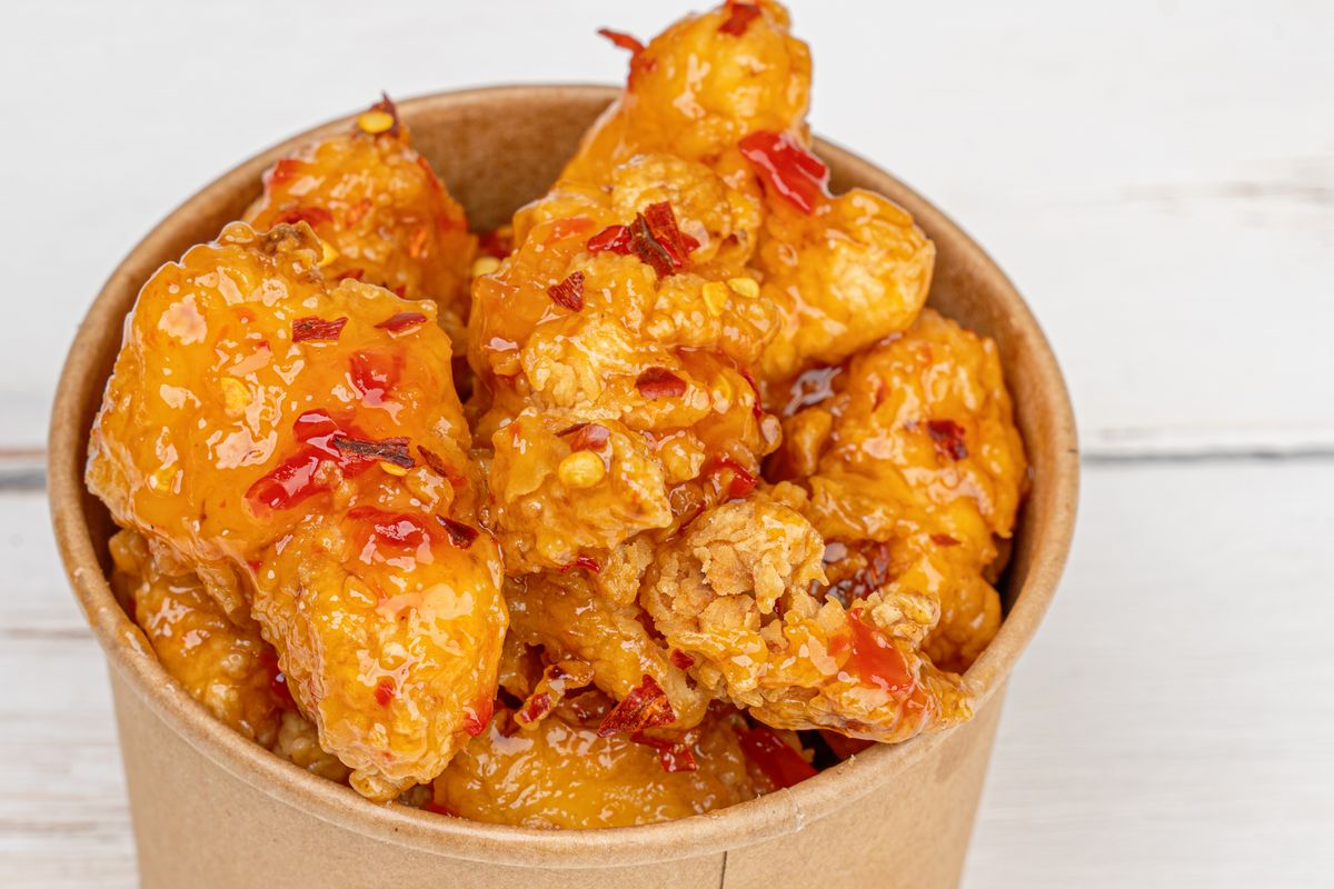 Delicious crispy fried chicken pieces in a cardboard cup with spicy glaze.