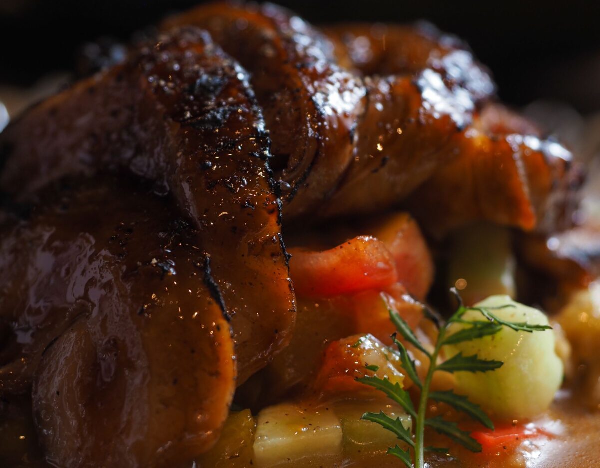 Delicious glazed roast duck served atop sautéed vegetables in a bowl.