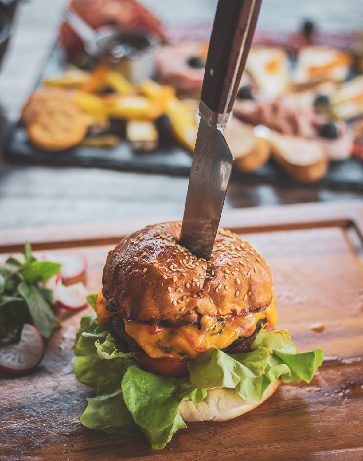 Before Chopped Cheese Went Viral, New York’s Bodegas Already Knew It Was a Star 1 Delicious gourmet burger topped with cheese and lettuce, stabbed with a knife, served on a wooden board.