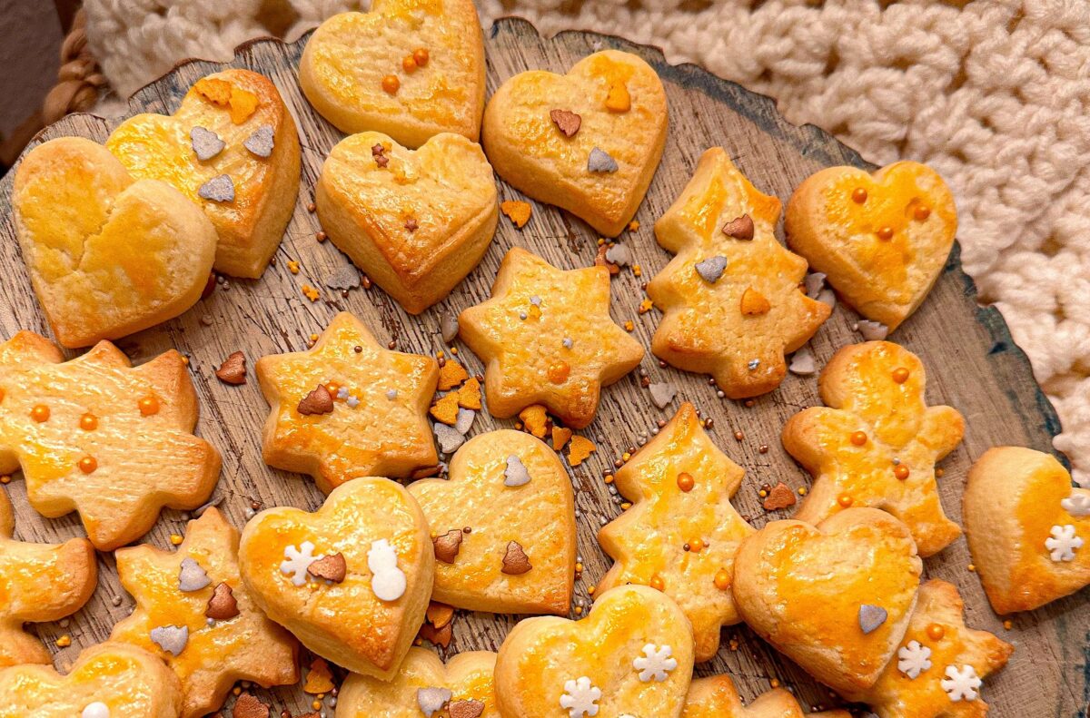 Delicious homemade Christmas cookies in festive shapes on a rustic wooden tray, perfect for the holiday season.