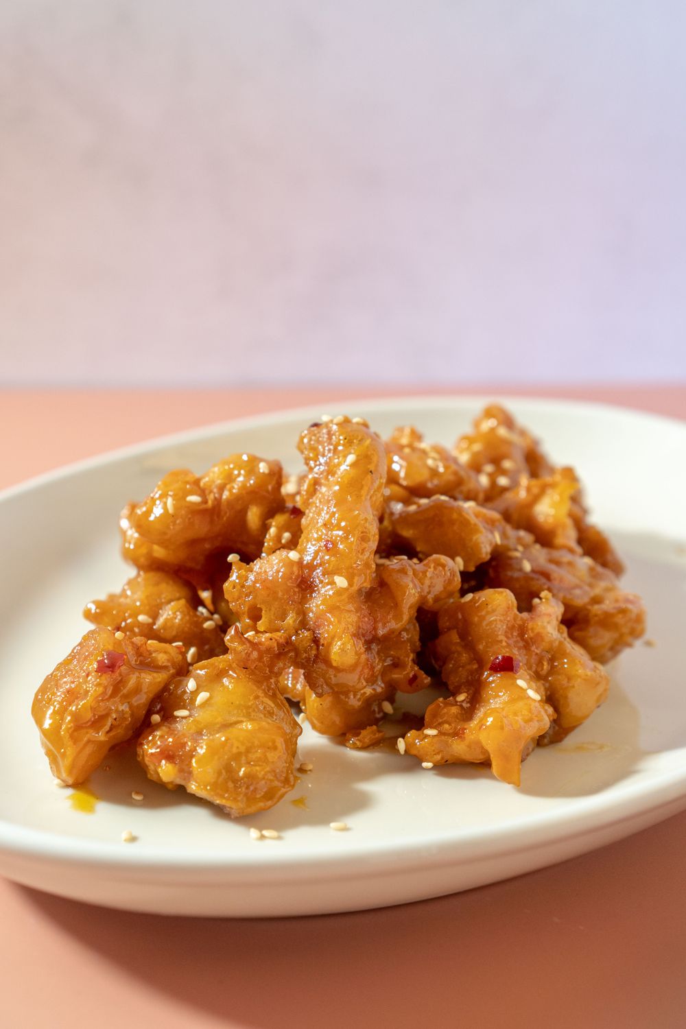 Delicious honey glazed fried chicken served on a white plate, showcasing Indonesian flavors.