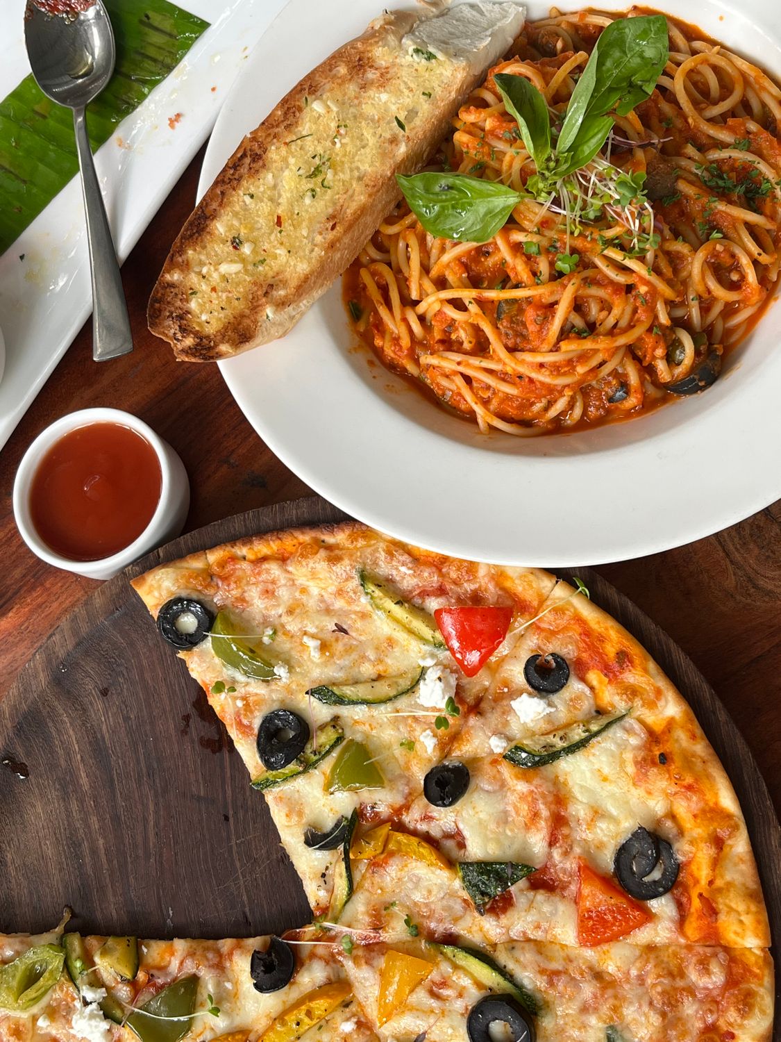 Delicious Italian meal with spaghetti, garlic bread, and veggie pizza, perfect for food lovers.