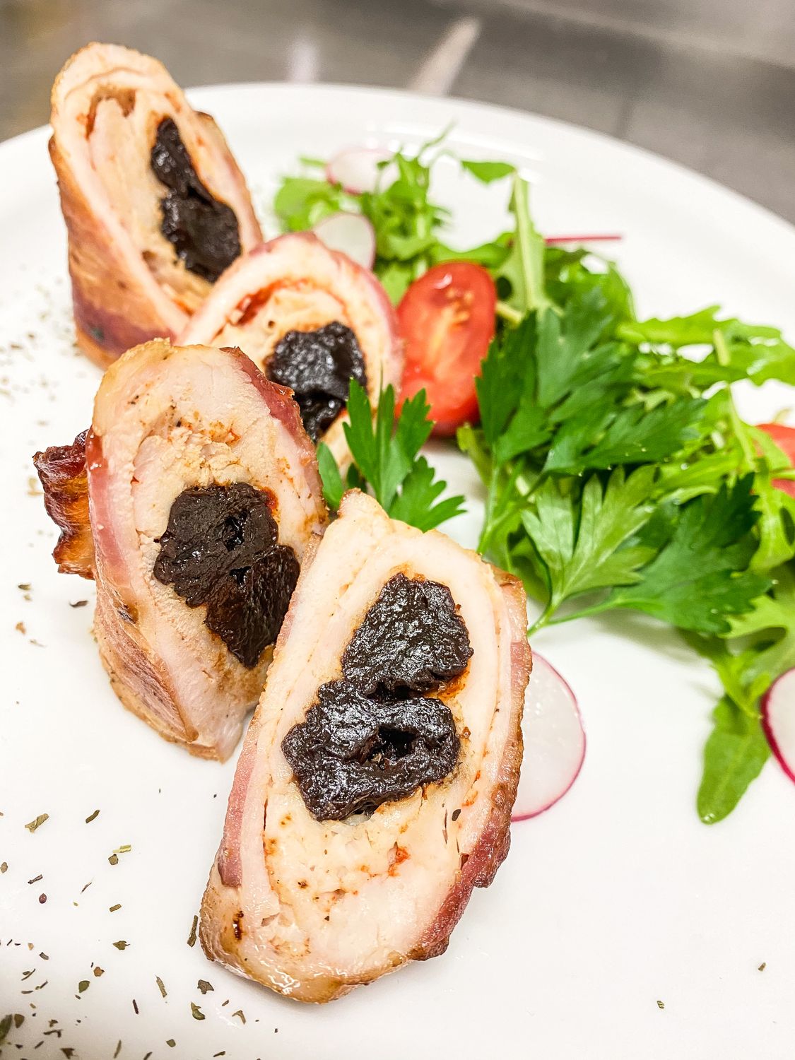 Prunes and Olives in Your Chicken Dinner? This Retro Classic Makes a Delicious Case 1 Delicious rolled chicken with prunes and fresh salad garnish, gourmet plating.