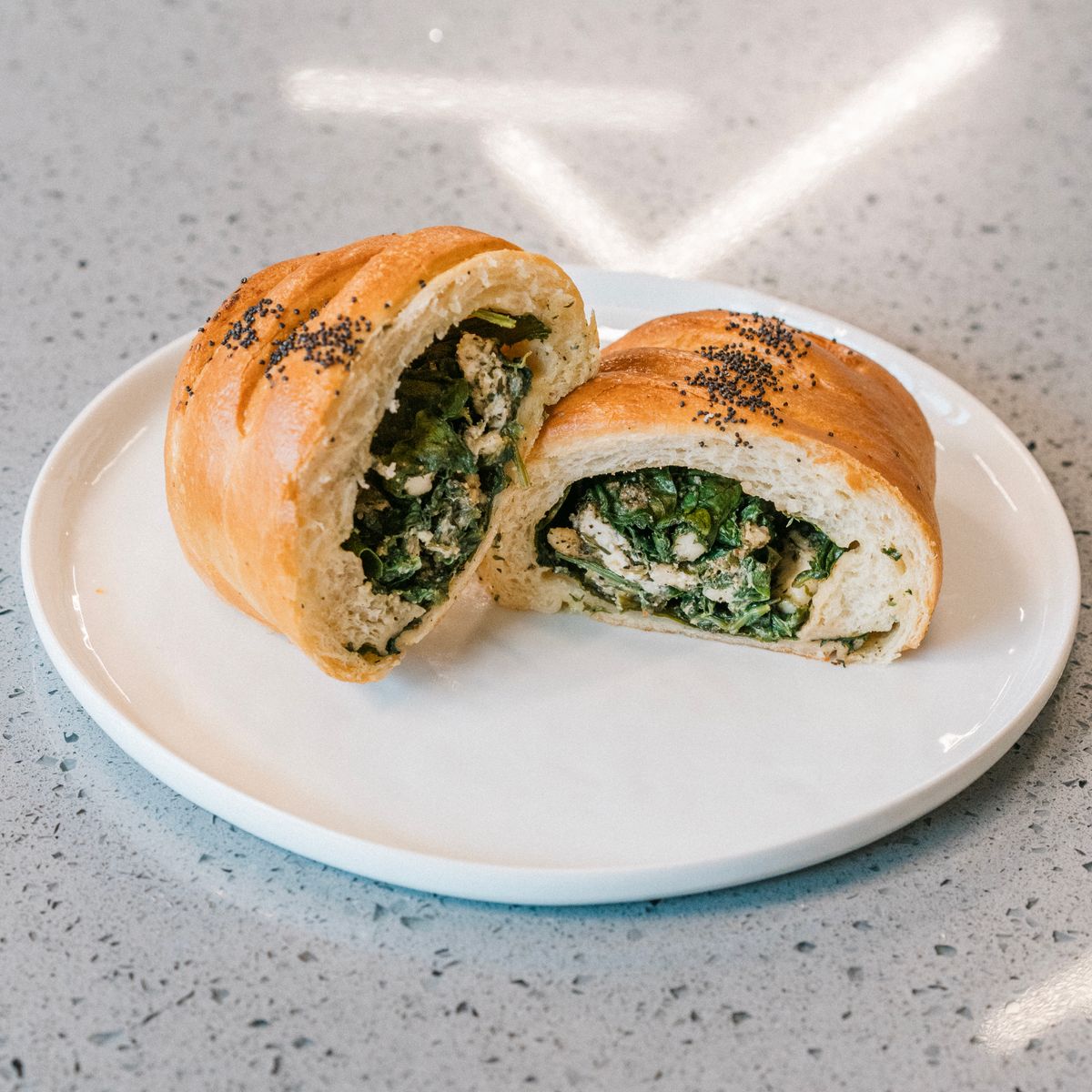 Delicious spinach and cheese stuffed bread on a white plate, perfect for breakfast.