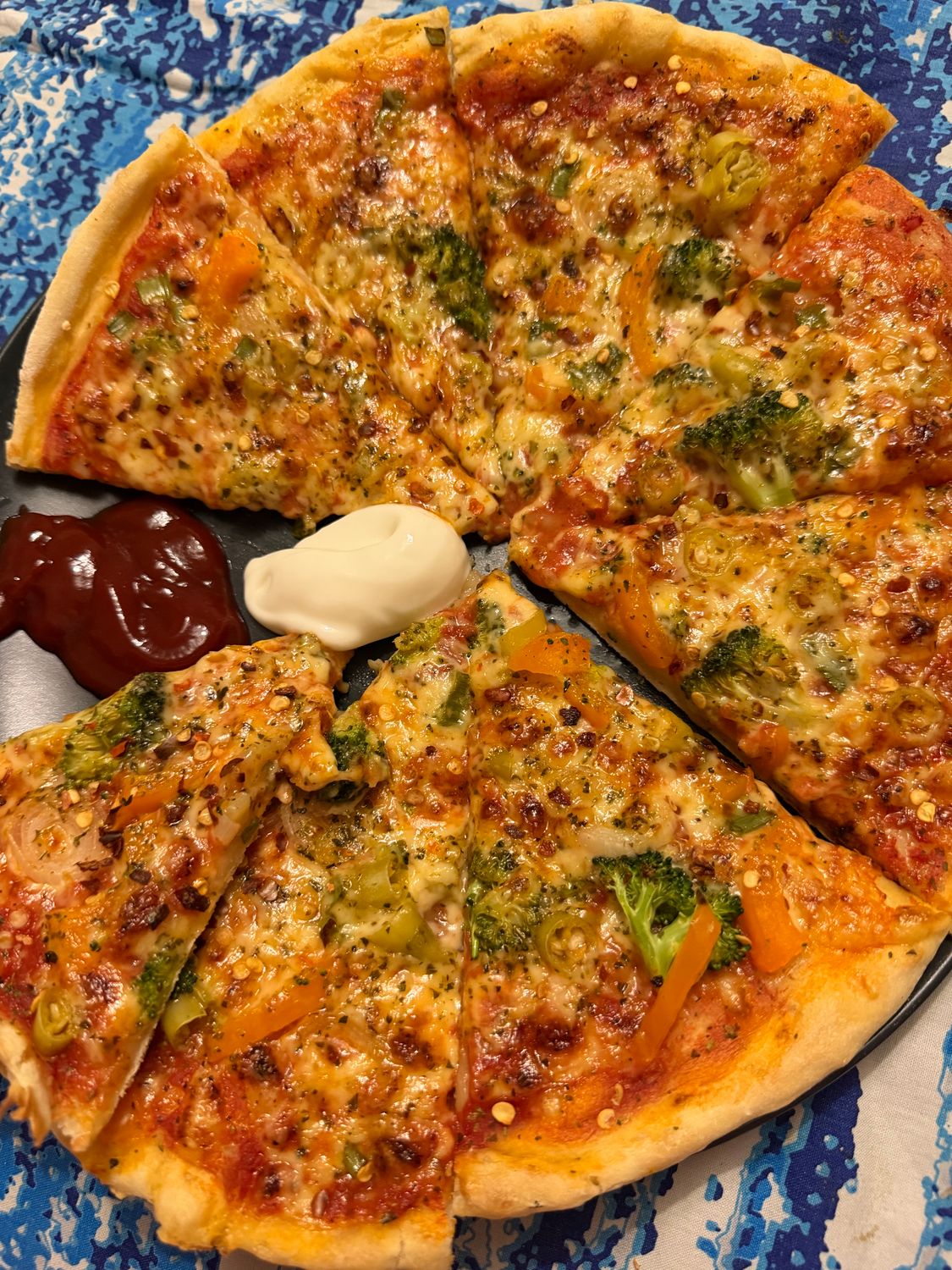 Delicious vegetable pizza topped with broccoli and bell peppers on a decorative plate.
