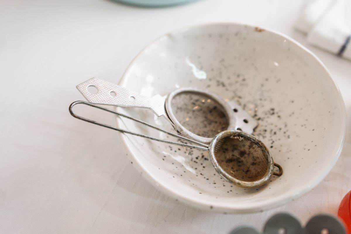 Detail of used kitchen sieve in a speckled ceramic bowl, conveying a rustic kitchen atmosphere.