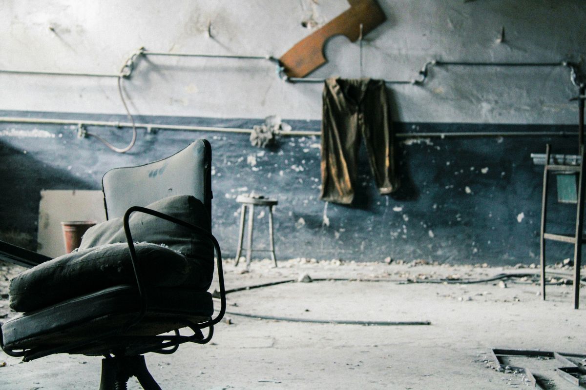 8 Things That Can Happen If You Stop Cleaning Your Home 1 Dusty chair in a deserted room with peeling walls and industrial decor. Captures urban decay.