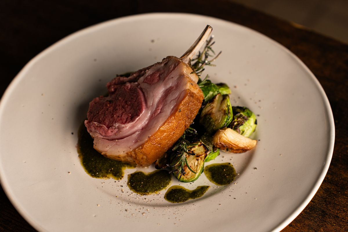 Elegant gourmet lamb rack presentation with Brussels sprouts and sauce, showcasing fine dining in Tokyo.