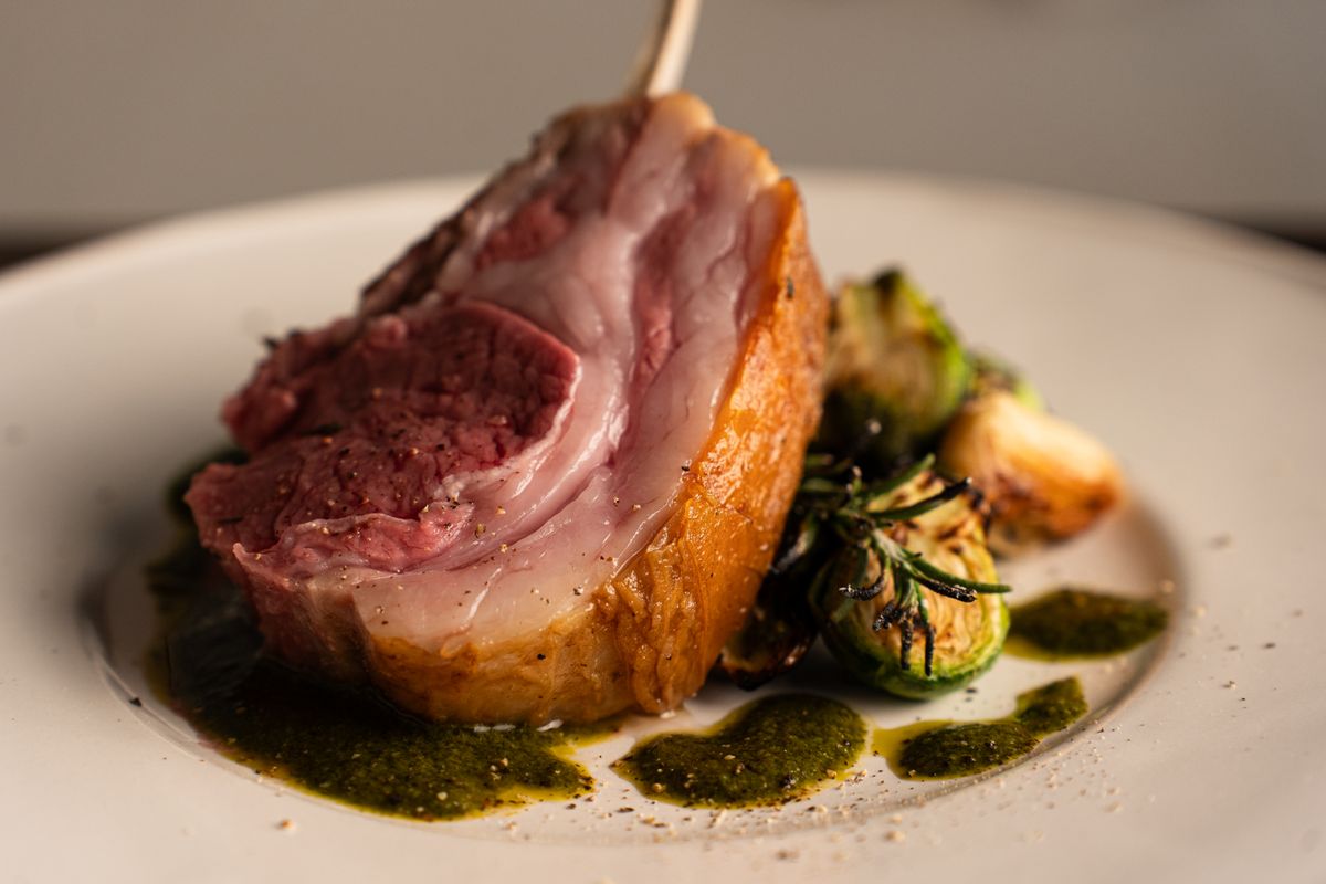 Elegant gourmet lamb rack with herb sauce and vegetables, capturing fine dining aesthetics.