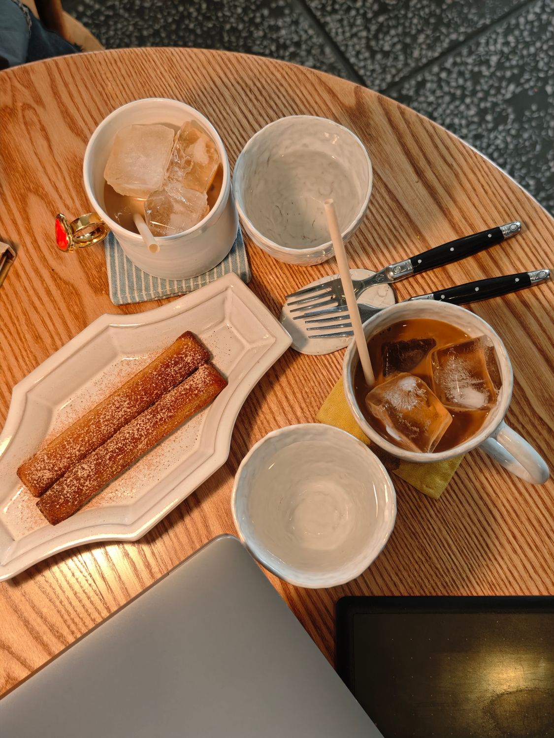 Flat lay of iced coffee mugs and churros on a wooden table, ideal for café ambiance.