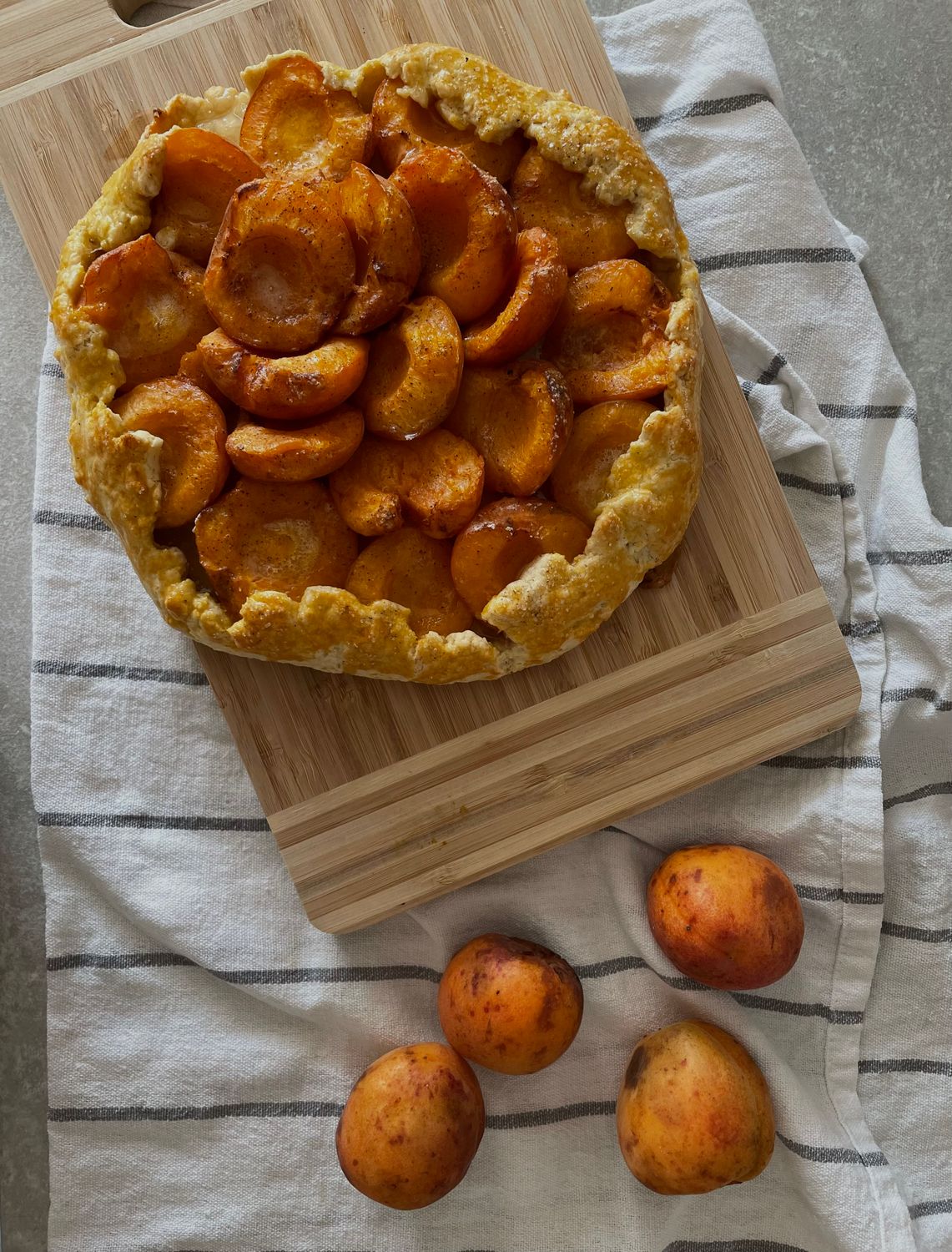 Forget Perfect Pie Crust, This Rustic Plum Galette Makes Messy Look Delicious 2 Freshly baked apricot galette on a cutting board, perfect for summer baking.