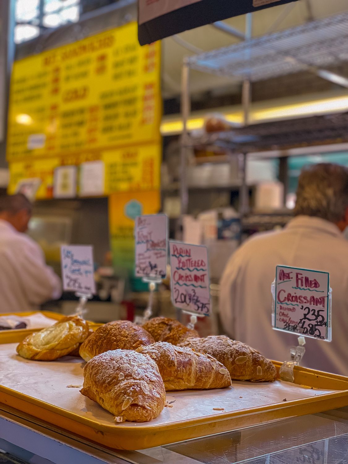 Freshly baked croissants showcased at a bustling bakery counter.
