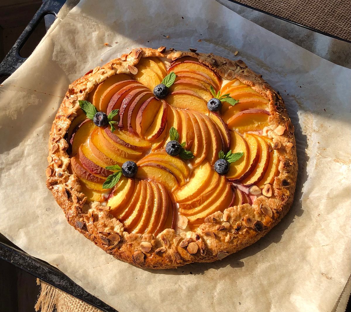 Freshly baked peach tart topped with blueberries, perfect for a summer dessert.