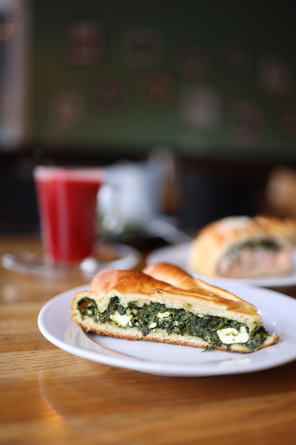 Freshly baked spinach and feta pastry with juice in a cozy cafe setting.