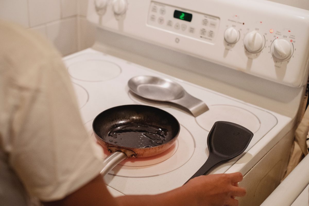 Butter or Oil for Seasoning Cast Iron? Here’s What Cookware Makers Recommend 1 From above of crop anonymous female standing near white stove preparing to fry food in kitchen