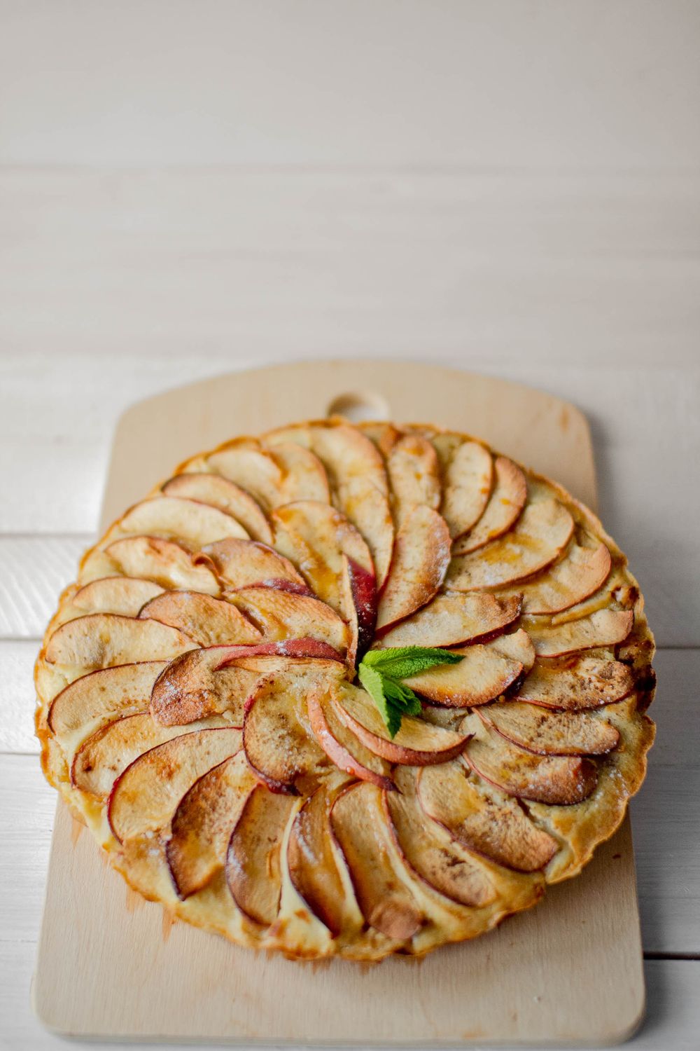 From above yummy apple tart served with mint leaves on cutting board on kitchen table
