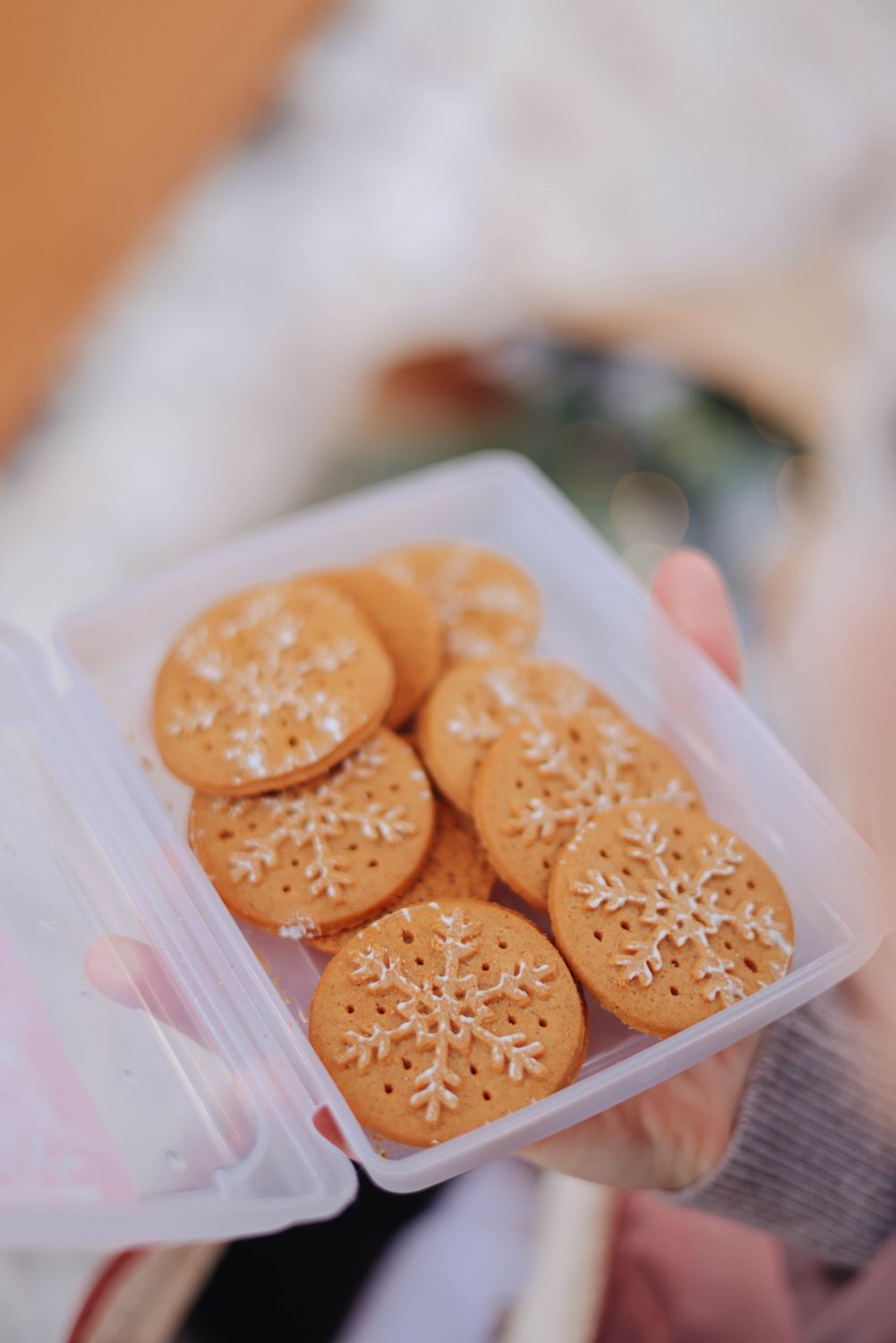 Homemade snowflake cookies in a clear container, perfect for holiday celebrations.