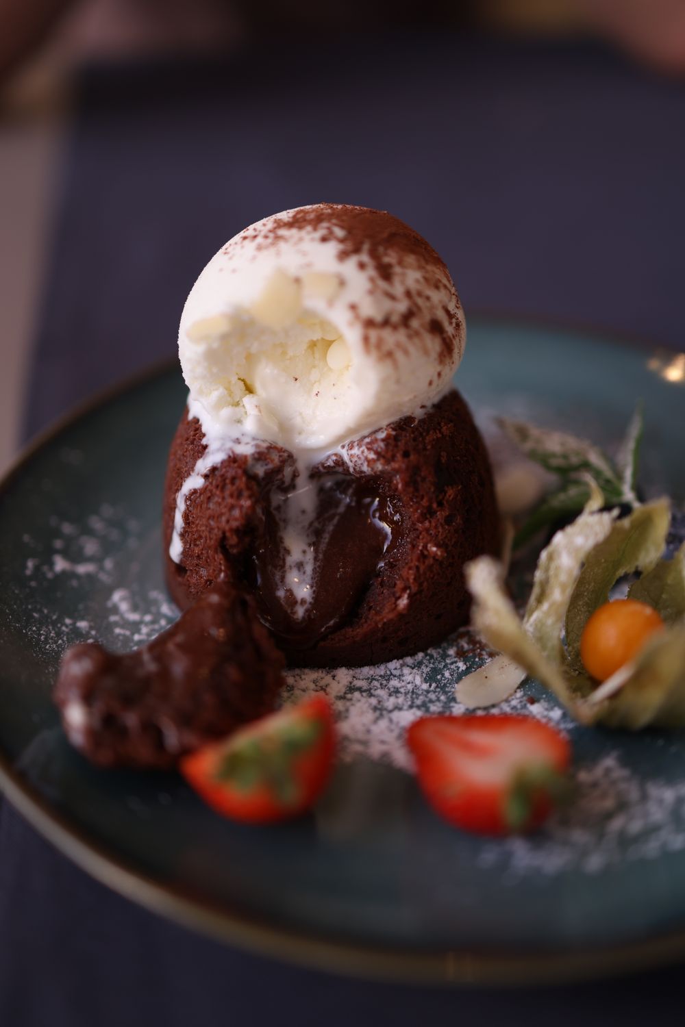Indulgent chocolate lava cake with ice cream, strawberries, and physalis.