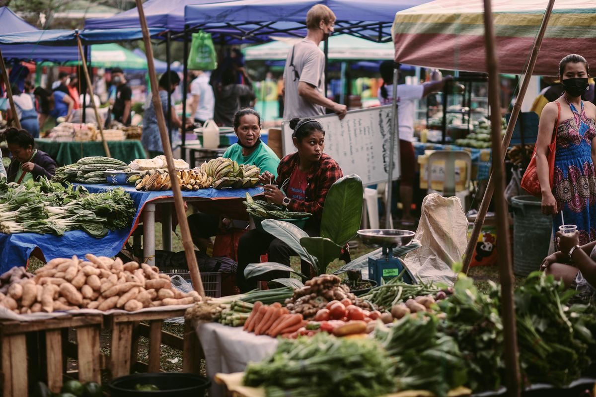 The Farmers Market Finds That Can Turn Into an Entire Weekend Menu 1 Lively outdoor market scene featuring fresh fruits and vegetables, local vendors, and diverse shoppers.