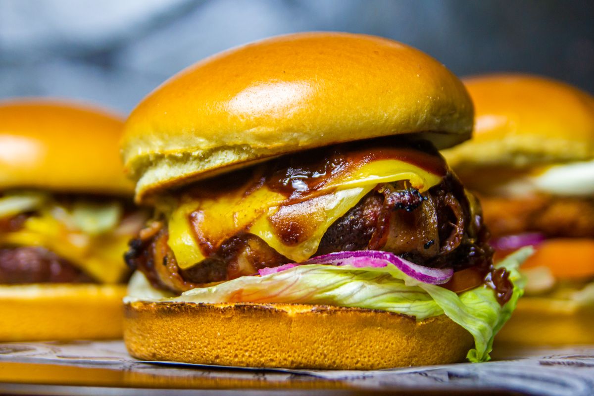 5 Simple Ways to Reheat Burgers Without Turning Them Tough 1 Mouthwatering beef burger topped with cheddar and onions, ideal for food lovers.