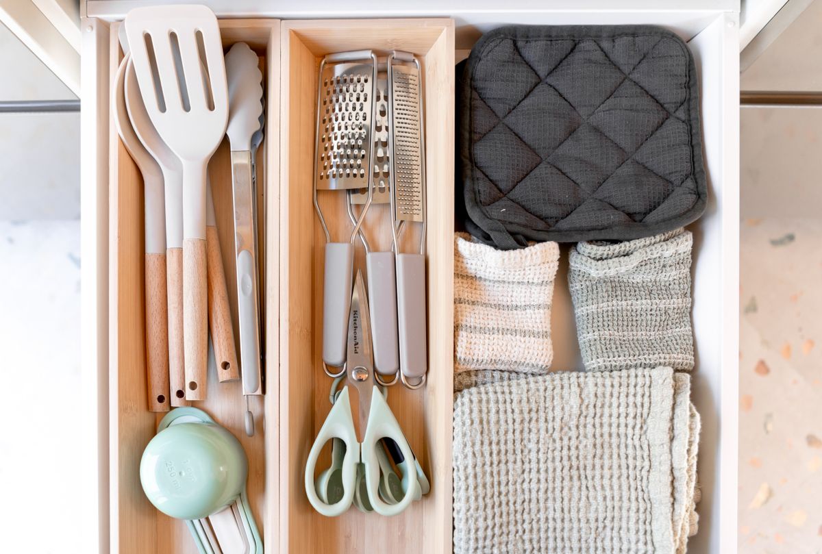 10 Kitchen Items Professional Organizers Tell Clients to Let Go Of 1 Neatly arranged kitchen tools and textiles in a drawer, showcasing an organized culinary space.