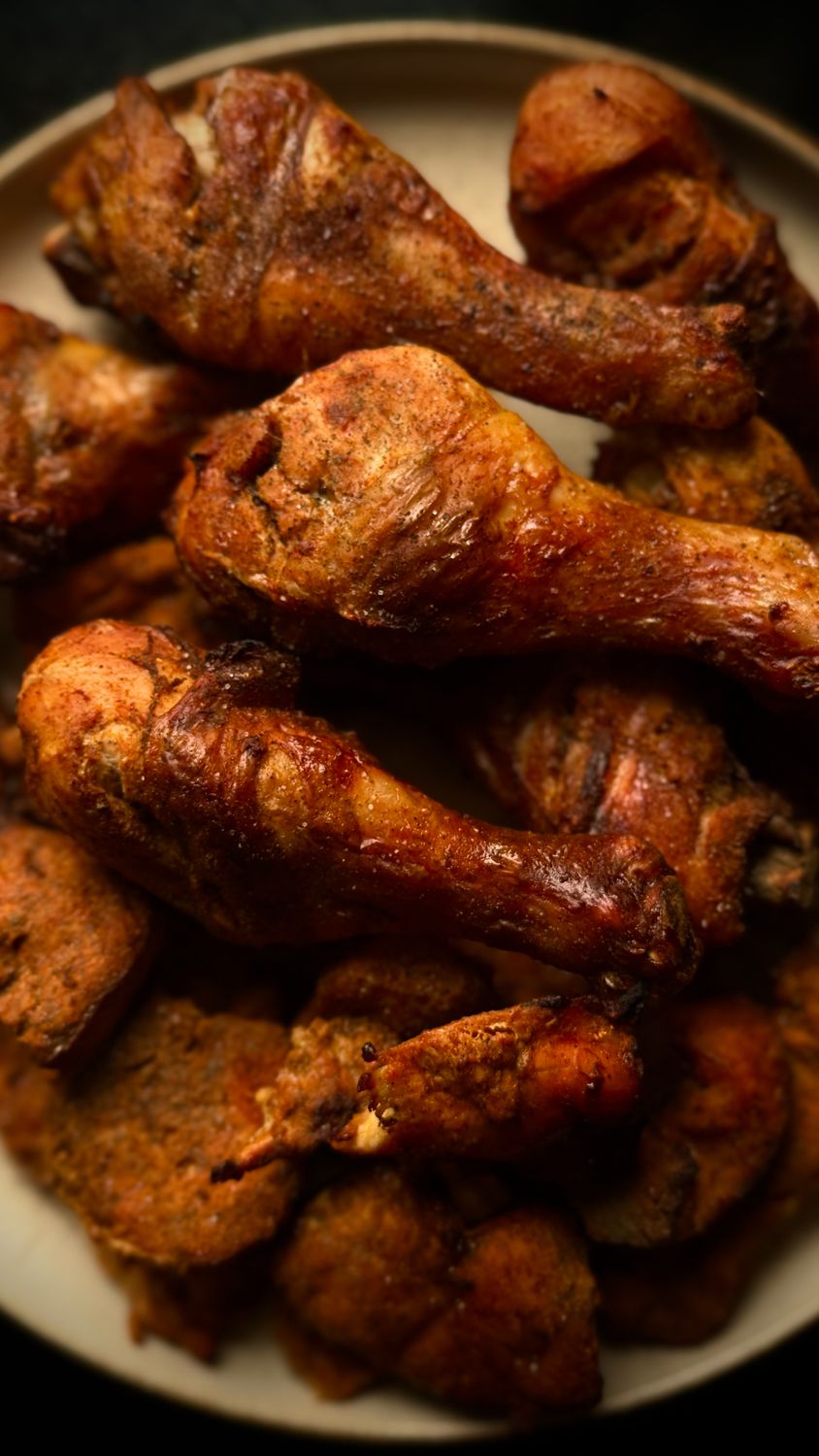 Plate of golden brown fried chicken drumsticks with crispy seasoning, perfect for a savory meal.