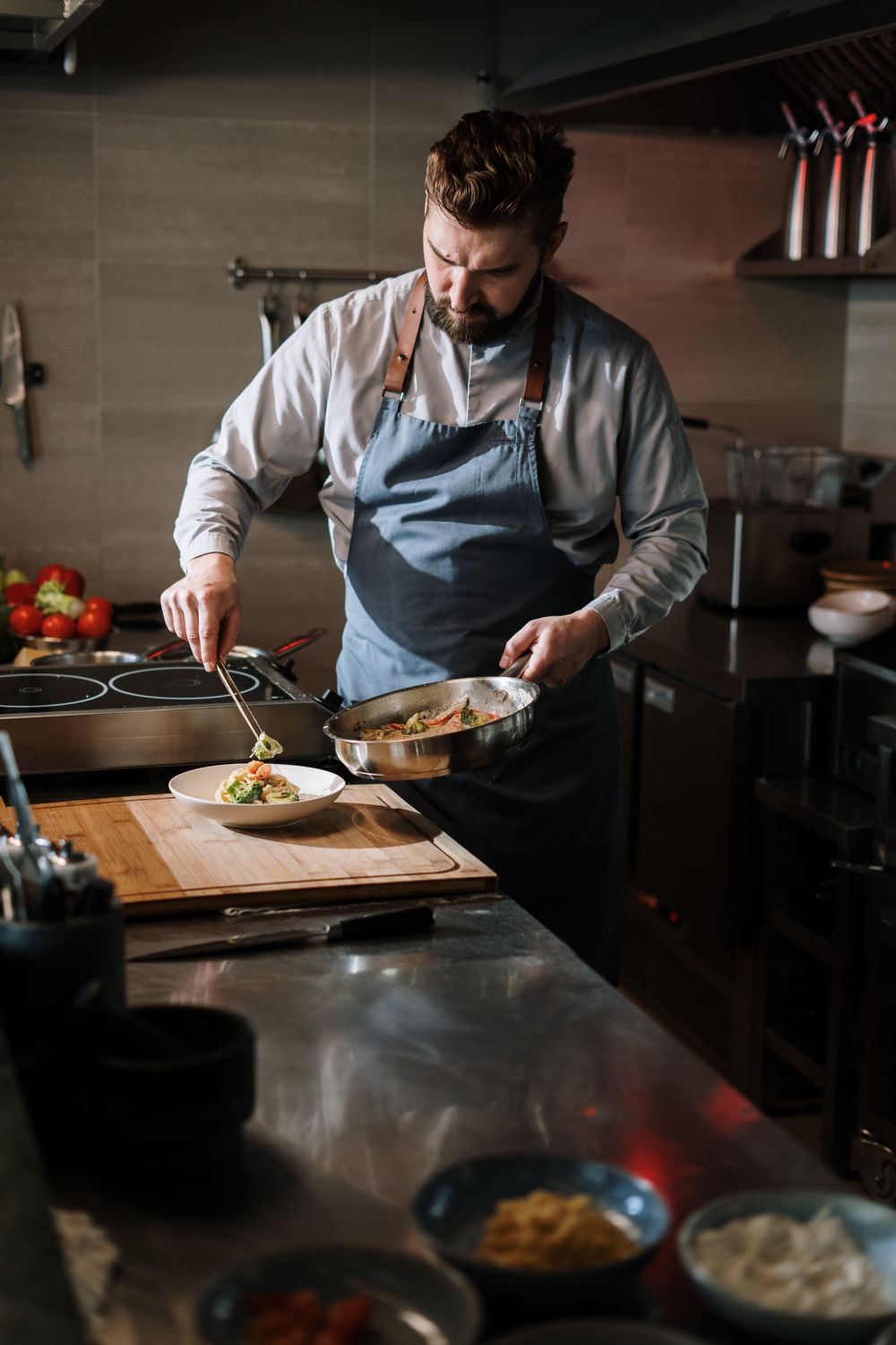 Professional chef plating a gourmet dish in a modern kitchen setting.