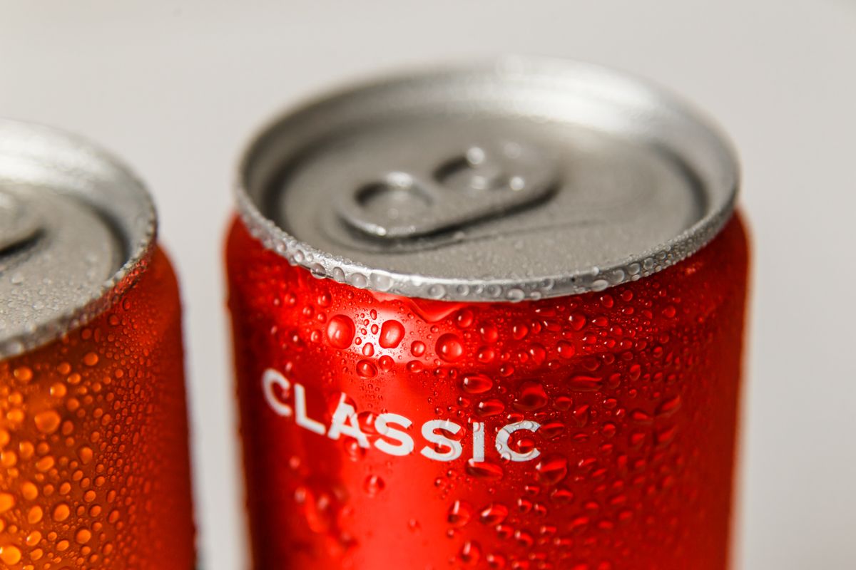 Refreshing close-up of wet red and orange soda cans with condensation droplets.