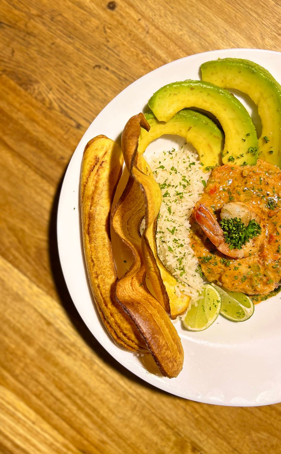 Savor a delicious Colombian meal with fried plantains, avocado, shrimp, and rice, showcasing vibrant flavors.