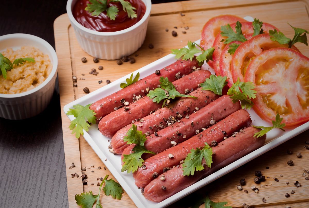 Savor a platter of hotdogs with fresh tomatoes and sauces, perfect for a fast food feast.