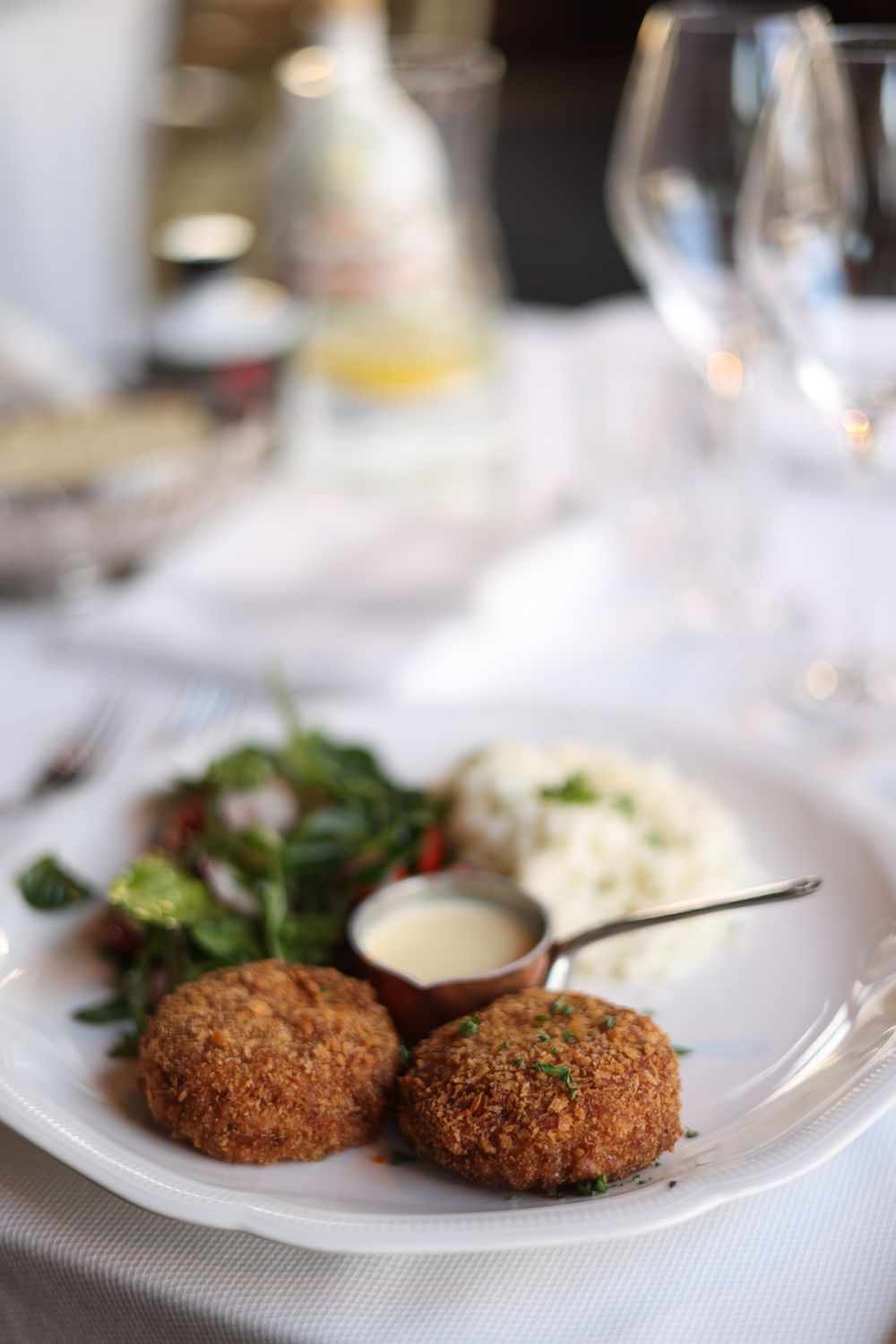 Tantalizing crab cakes served with fresh salad and rice on an elegant table setting.