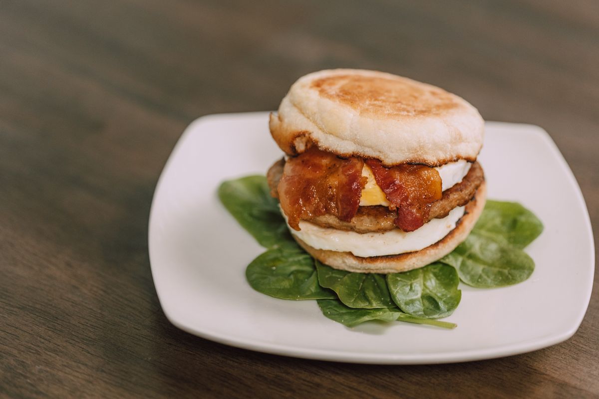 Homemade English Muffins Have One Delicious Catch: You Might Want to Make Them Again 2 Tasty bacon and egg sandwich on a plate with fresh spinach garnish.