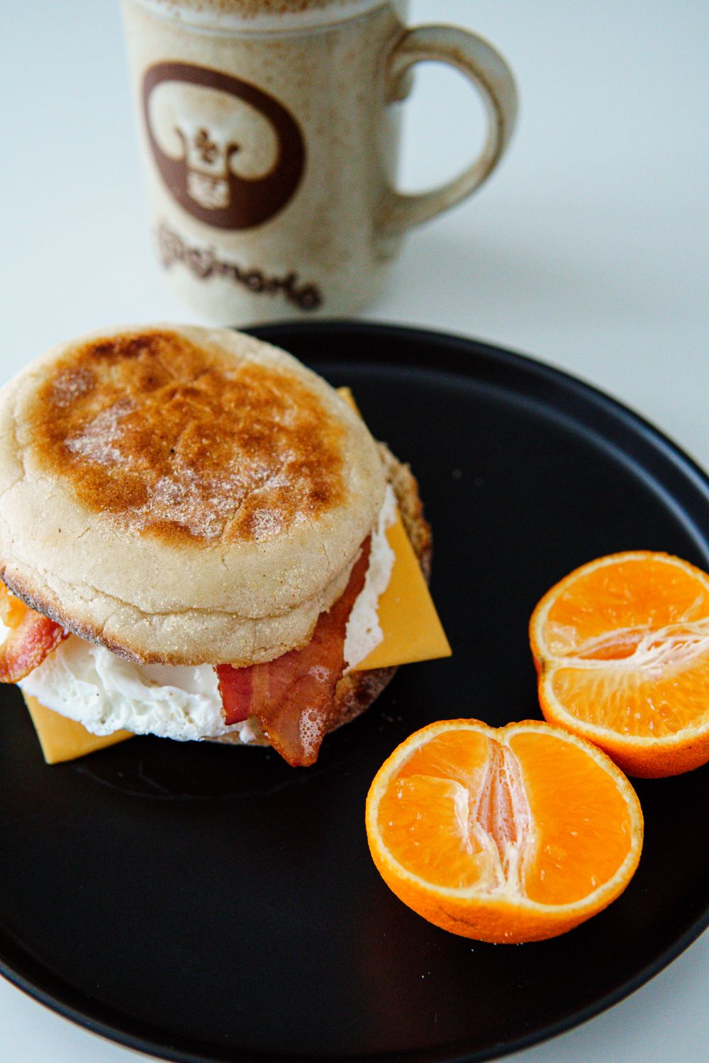 Homemade English Muffins Have One Delicious Catch: You Might Want to Make Them Again 1 Tasty breakfast with a bacon, egg, and cheese muffin served with fresh tangerines and coffee.