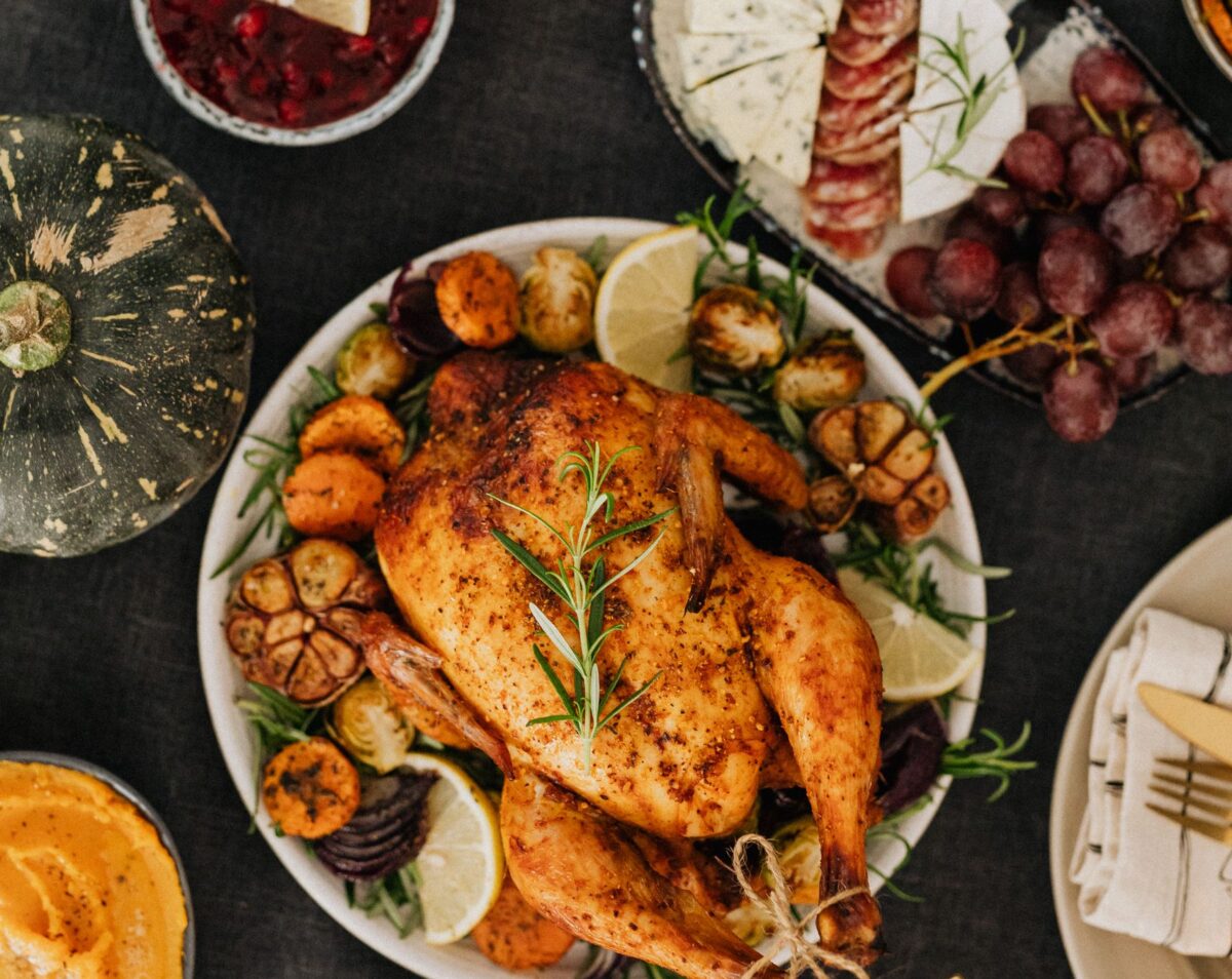 Top-down view of a Thanksgiving feast featuring roasted chicken, sides, and wine.