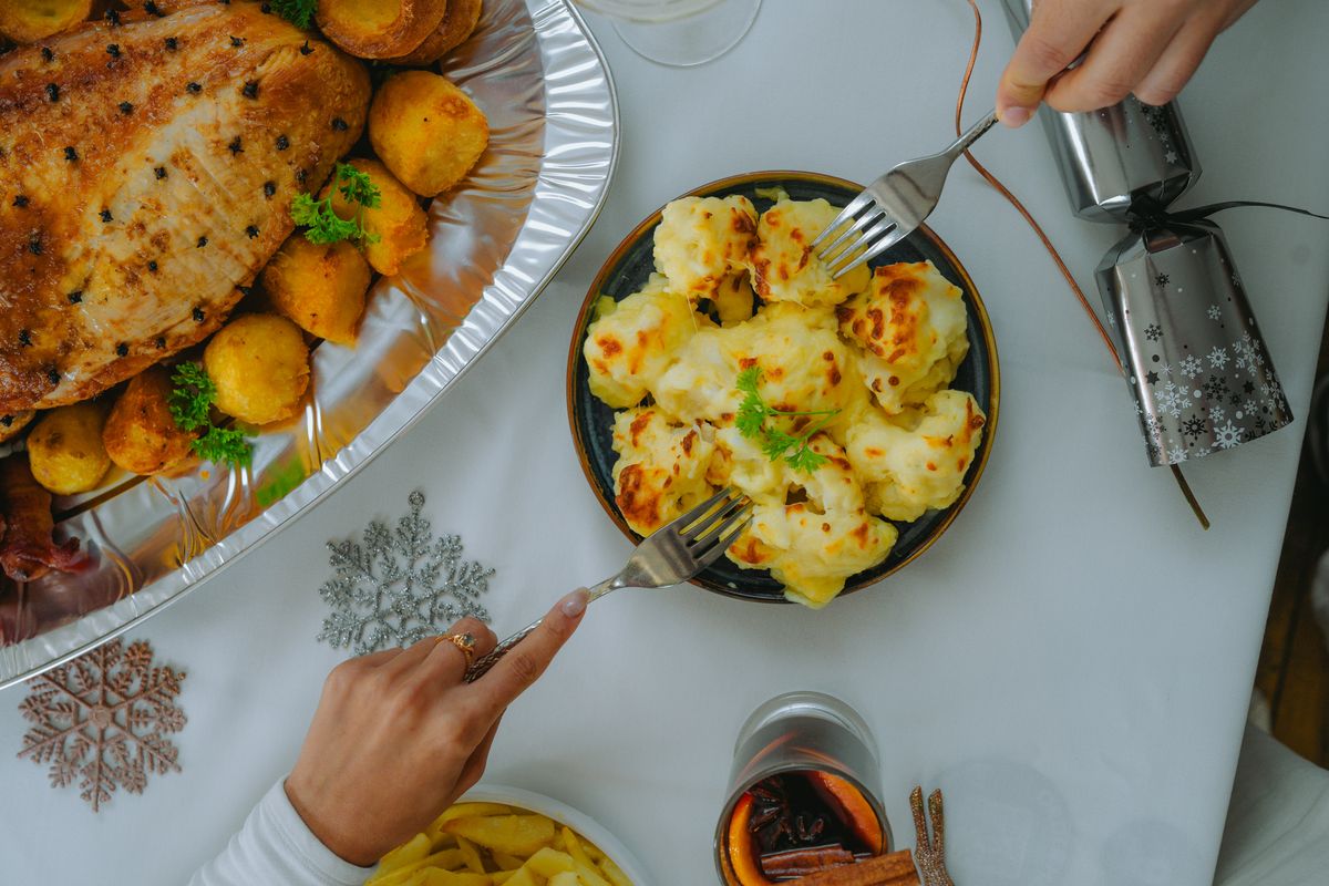 Top view of a festive meal featuring roasted meat, cheese potatoes, and holiday decor.