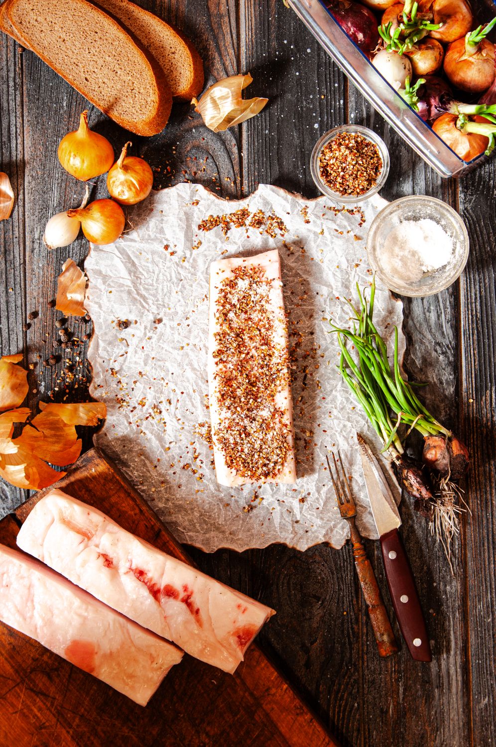 Beef Tallow Is Sizzling Again And Restaurants Are Betting Diners Will Taste the Difference 2 Top view of salted pork with herbs and spices on rustic kitchen table with bread and onions.