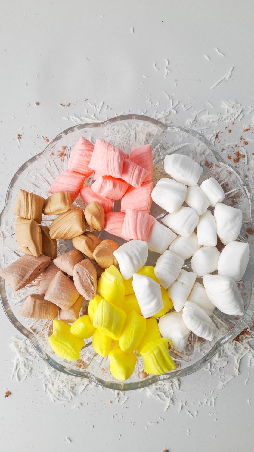 Top view of vibrant candies arranged on a glass plate with a white background.
